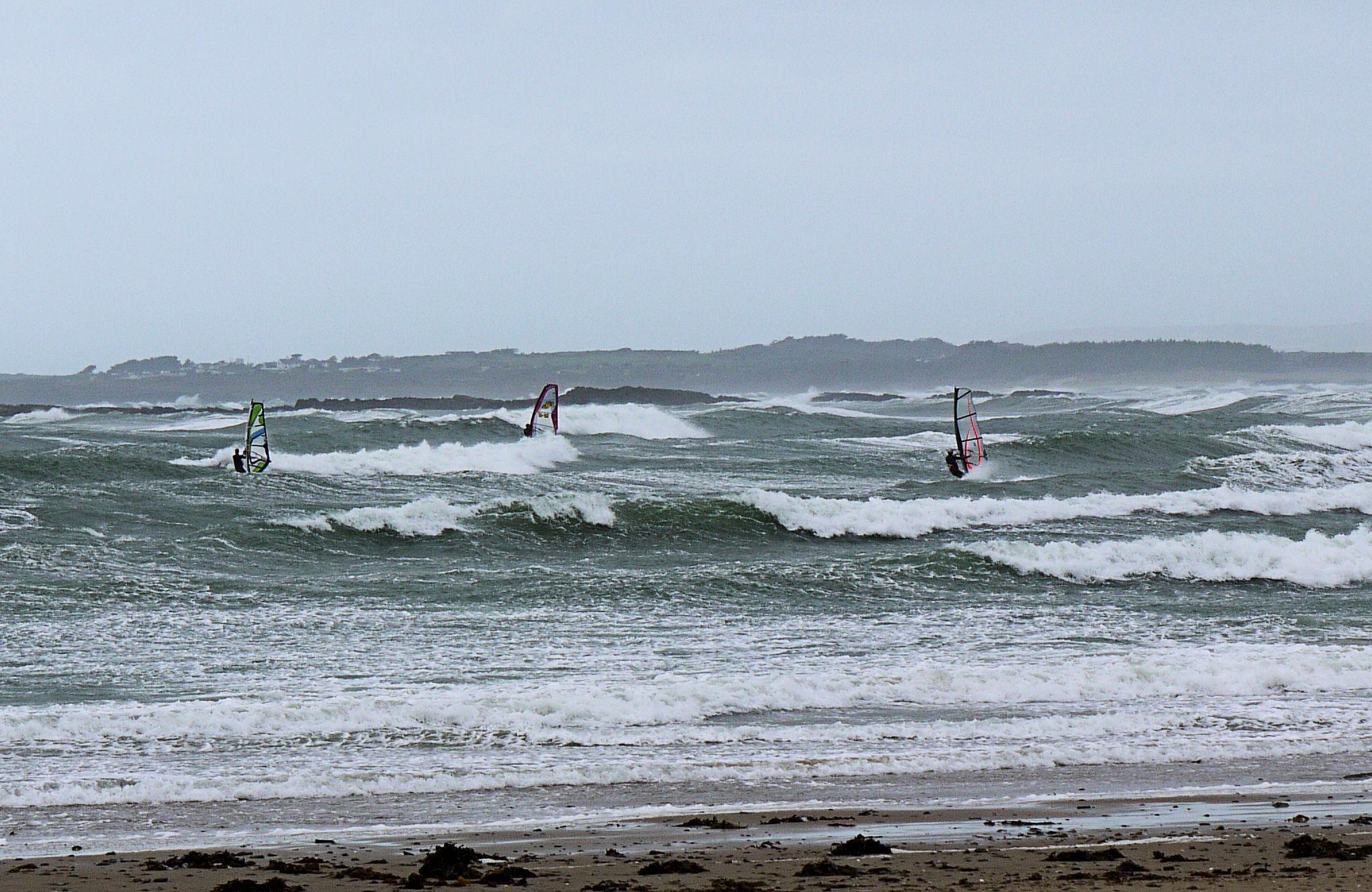 Rhosneigr beach Anglesey west coast with kitesurfers riding the Atlantic swell under dramatic skies