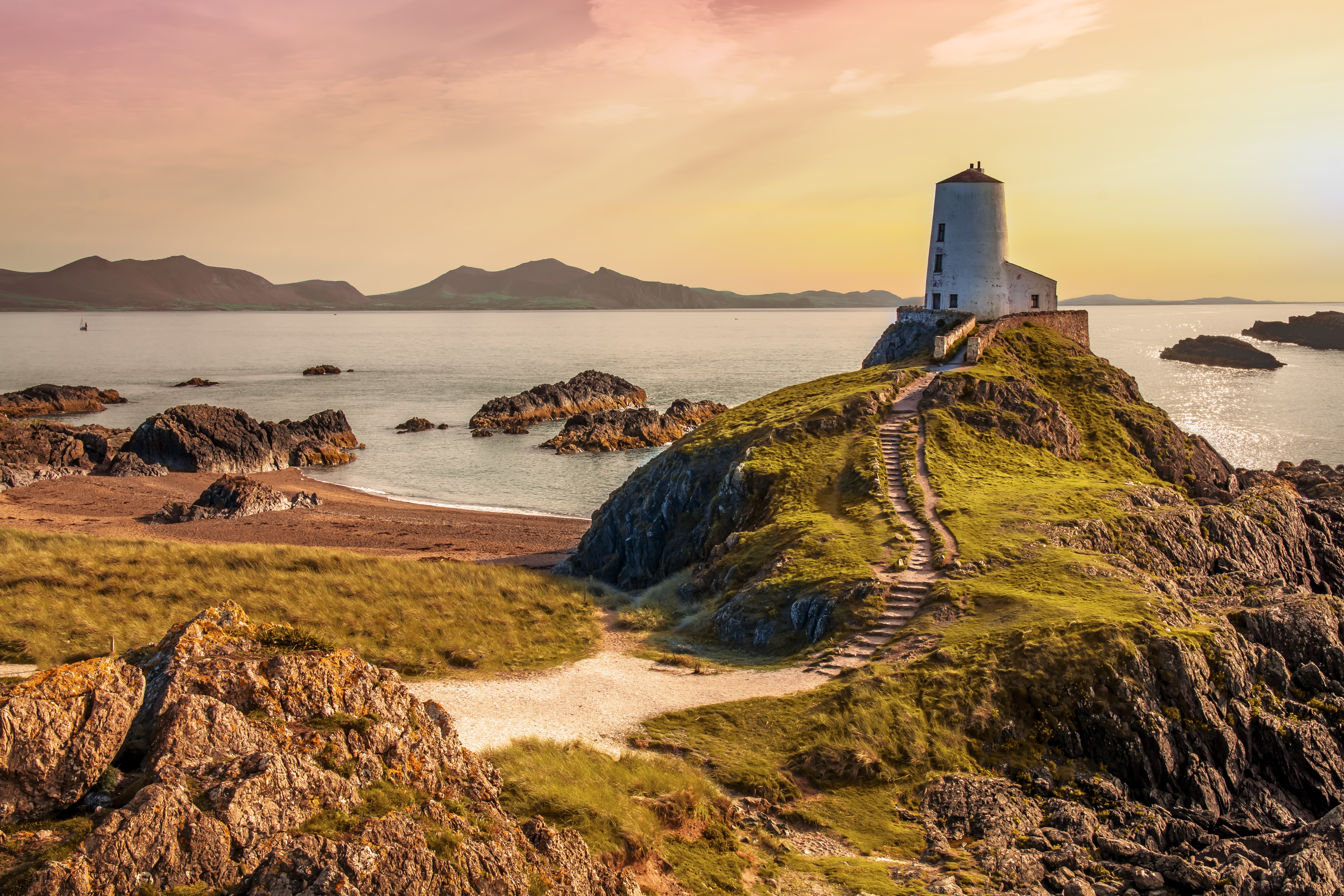 Llanddwyn Island beach Anglesey Wales with the ruined Twr Bach lighthouse and Snowdonia's peaks across the water