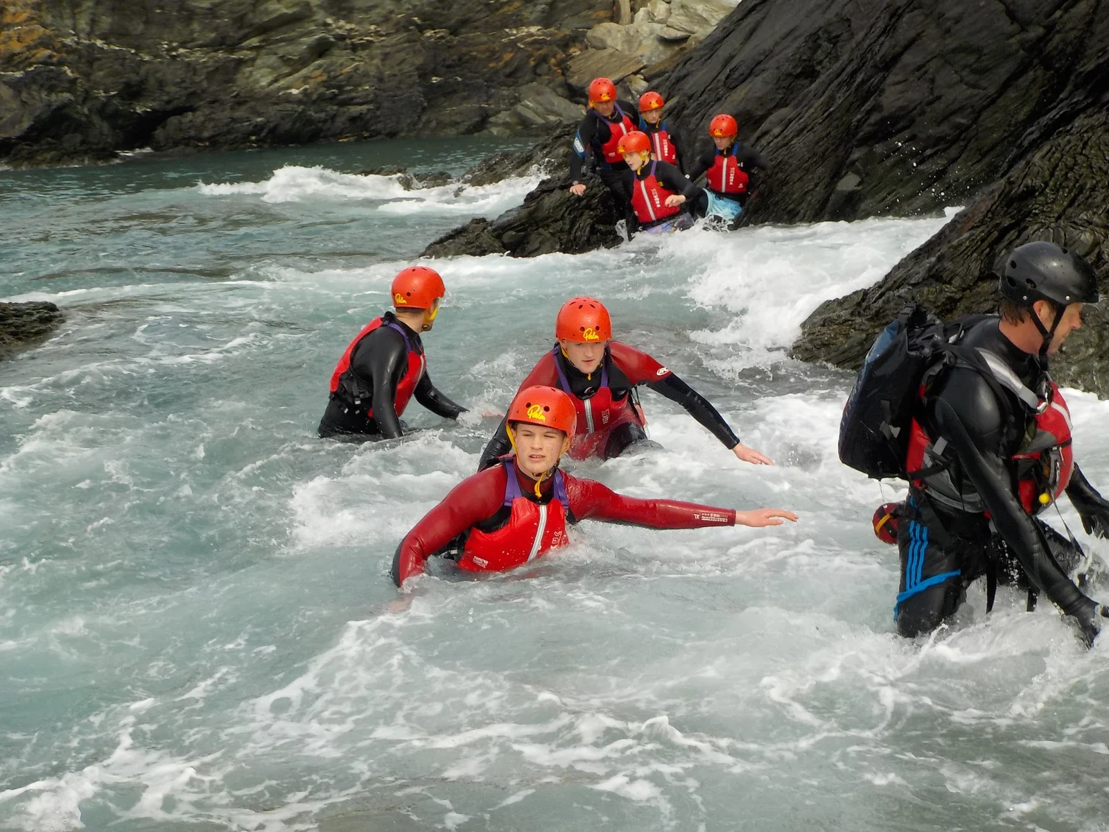 Coasteerer jumping from volcanic sea cliffs into clear turquoise water on Holy Island, Anglesey
