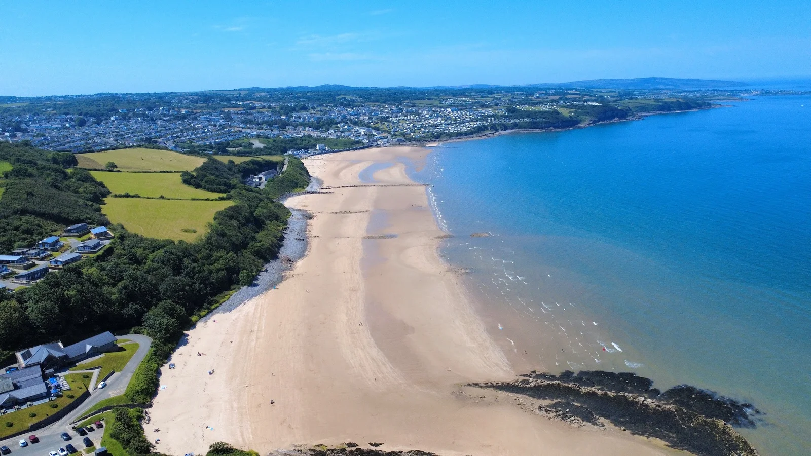 Golden sandy beach at Benllech on Anglesey's east coast with low cliffs and blue summer skies