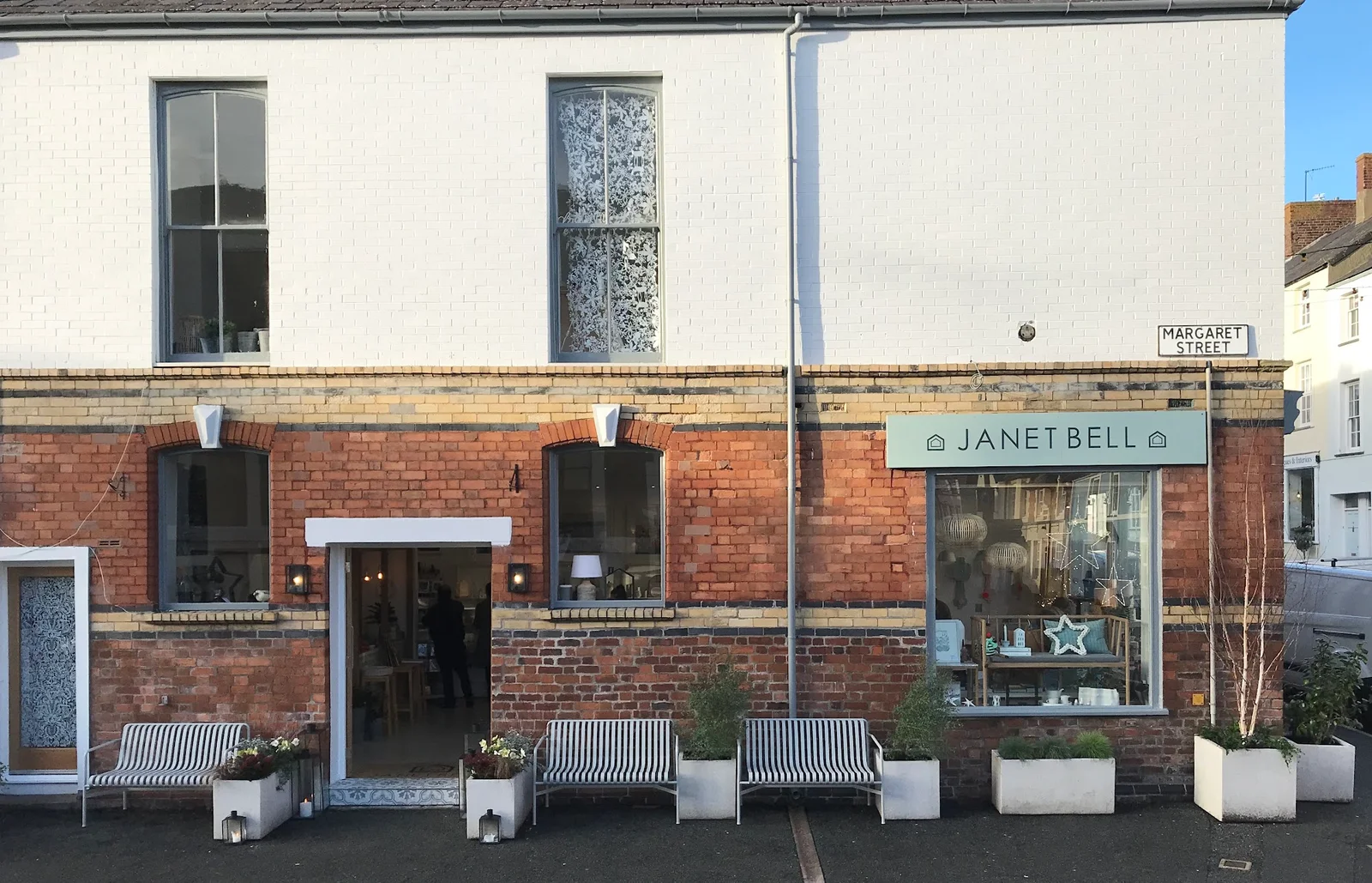 The street-front of Janet Bell Gallery & Lifestyle Store in Beaumaris, Anglesey, with striped benches outside