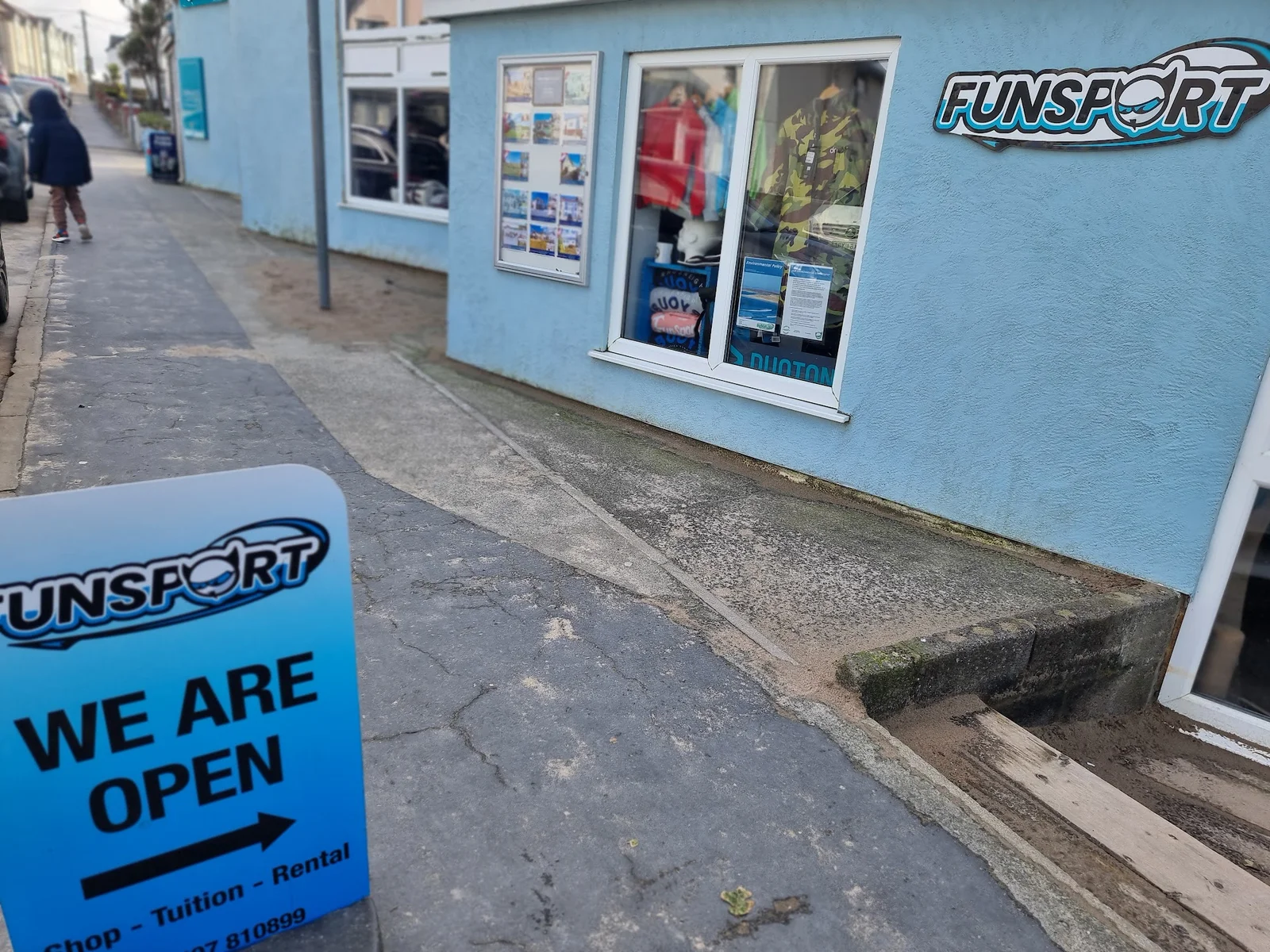 Kitesurfer riding the Atlantic swell at Rhosneigr beach with a large kite against a blue sky