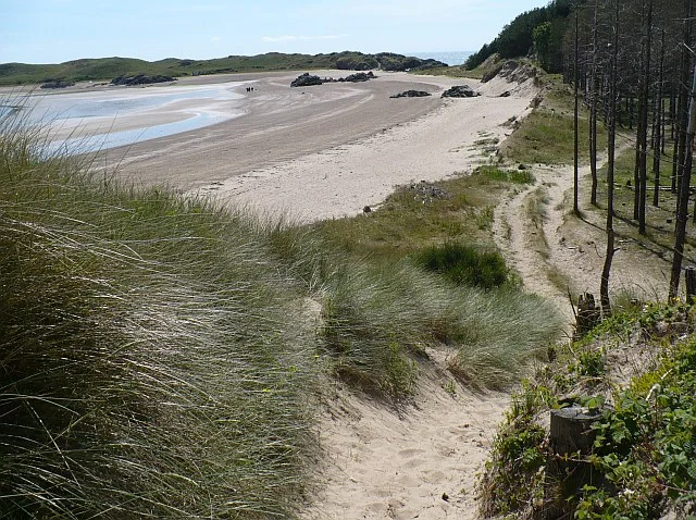 Llanddwyn Island beach Anglesey Wales with the ruined Twr Bach lighthouse and Snowdonia's peaks across the water