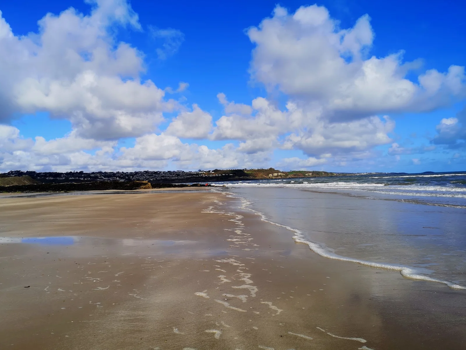 Vast tidal flats of Red Wharf Bay (Traeth Coch) at low tide with golden evening light across the sand