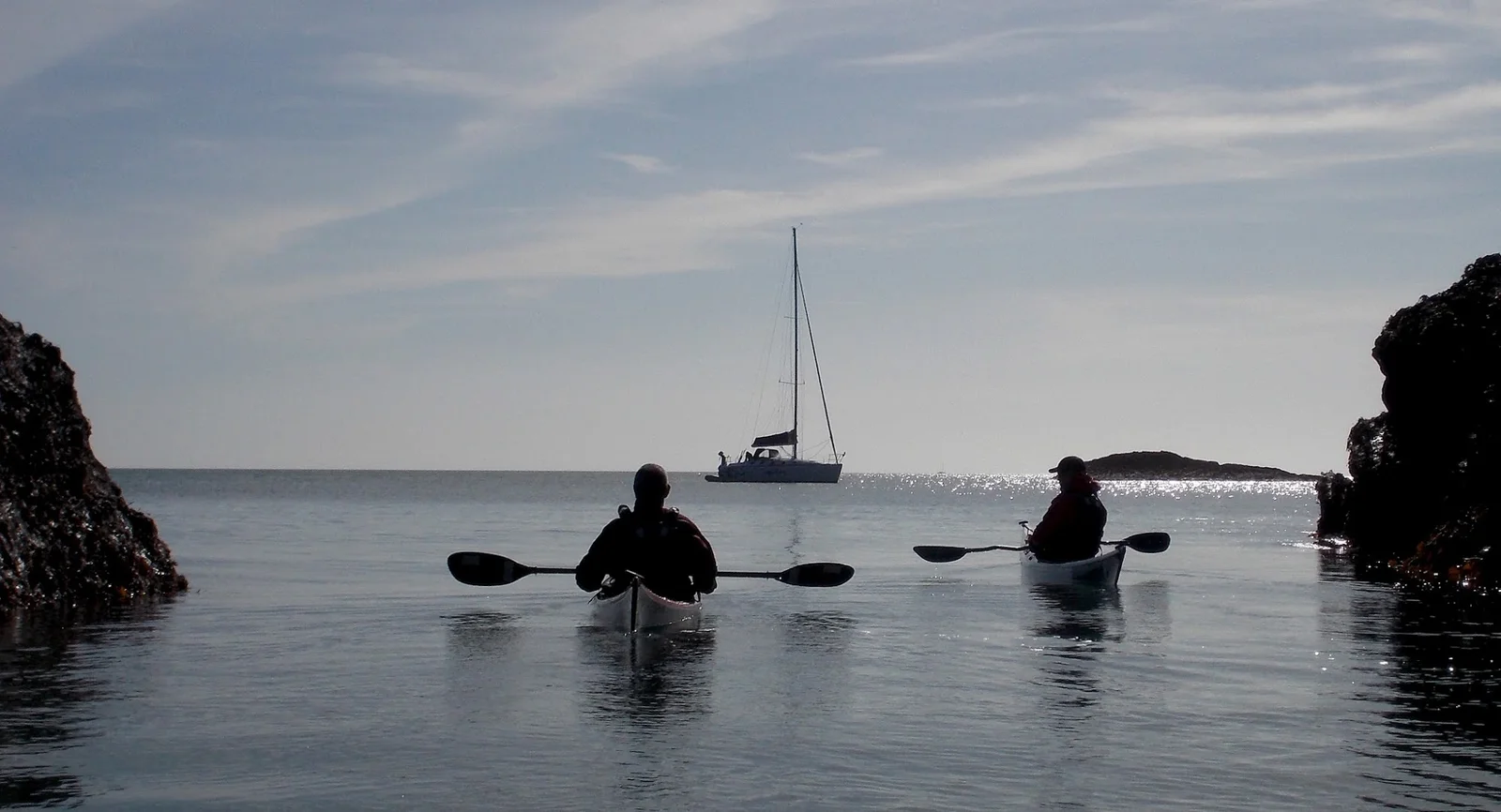 Sea kayakers paddling the Menai Straits with Snowdonia's peaks visible across the water