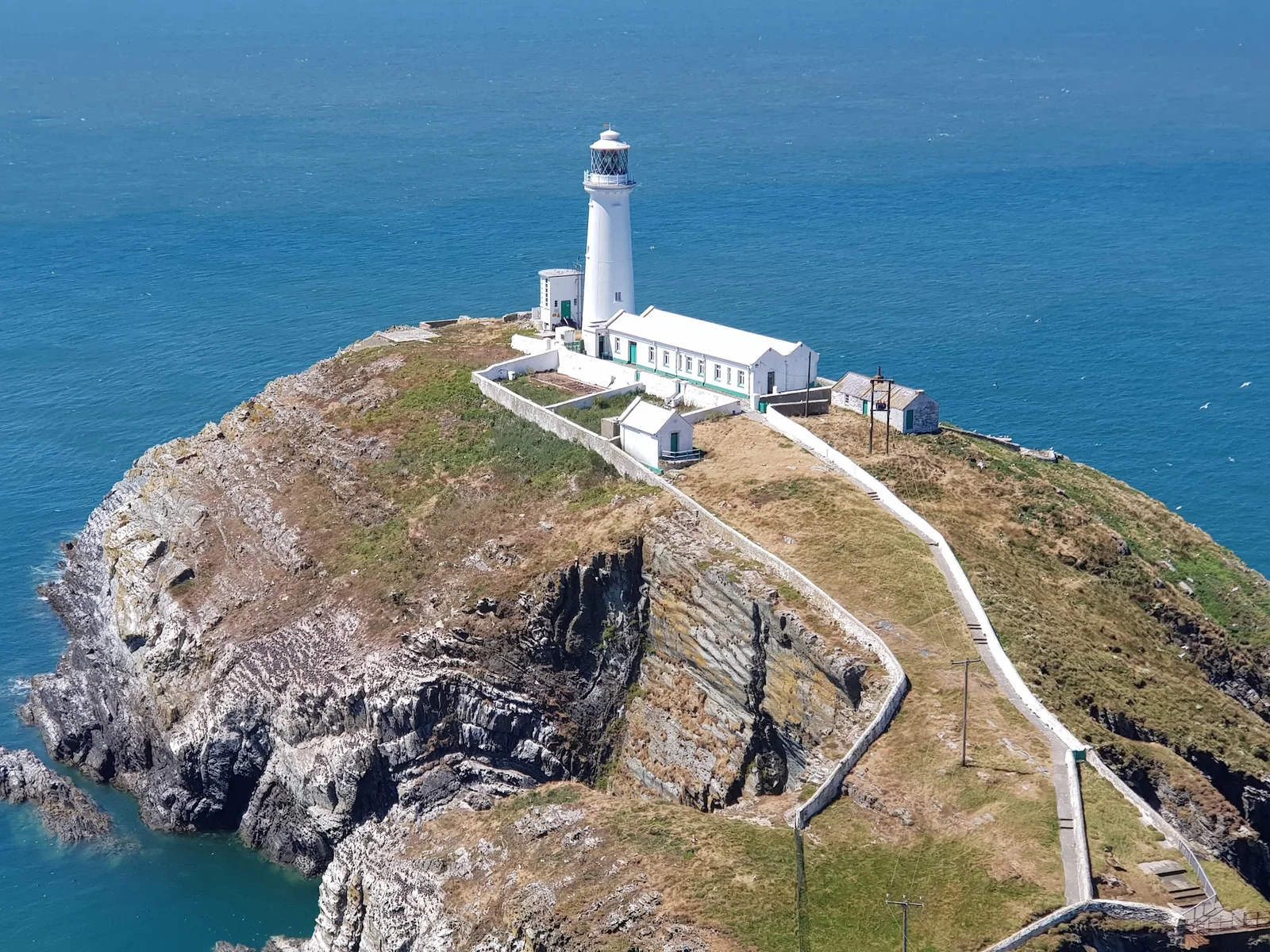 South Stack Lighthouse perched on its rocky islet off Holy Island cliffs, connected by a suspension bridge over churning seas